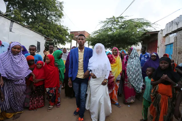 Somali couple Mohamed Noor (centre L) and Huda Omar walk through Rajo camp during their wedding ceremony in Mogadishu, Somalia August 17, 2016. (Photo by Feisal Omar/Reuters)