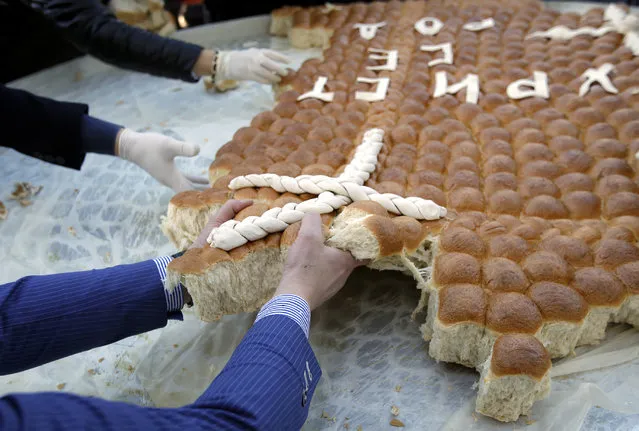 People break traditional Christmas bread to mark the Orthodox Christmas Day festivities in Belgrade, Serbia, Sunday, January 7, 2018. Children traditionally scramble for a piece of the bread, searching for a gold coin, hidden inside. (Photo by Darko Vojinovic/AP Photo)