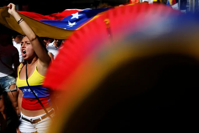 Protesters hold a Venezuelan flag during a demonstration to demand a referendum to remove Venezuela's President Nicolas Maduro, in Madrid, Spain, September 4, 2016. (Photo by Susana Vera/Reuters)