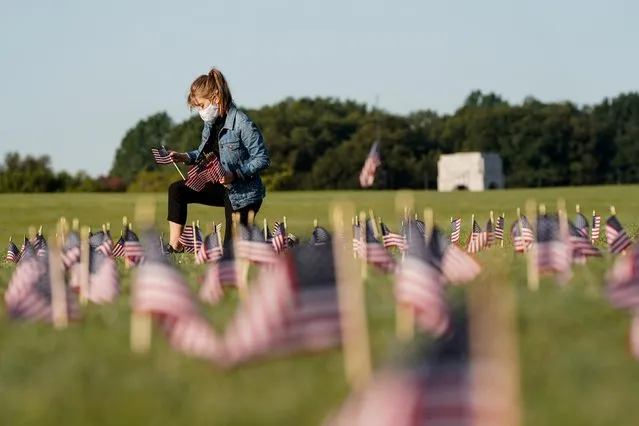 A volunteer places American flags representing some of the 200,000 lives lost in the United States in the coronavirus disease (COVID-19) pandemic on the National Mall in Washington, U.S., September 22, 2020. (Photo by Joshua Roberts/Reuters)