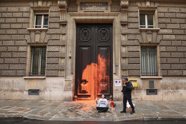 French police stand by an activist of environmental group “Riposte Alimentaire” (Food Retaliation) after she threw a bucket of orange paint against the doorway of the French Ministry of Agriculture to protest for food sustainability in Paris, on May 29, 2024. (Photo by Sami Karaali/AFP Photo)