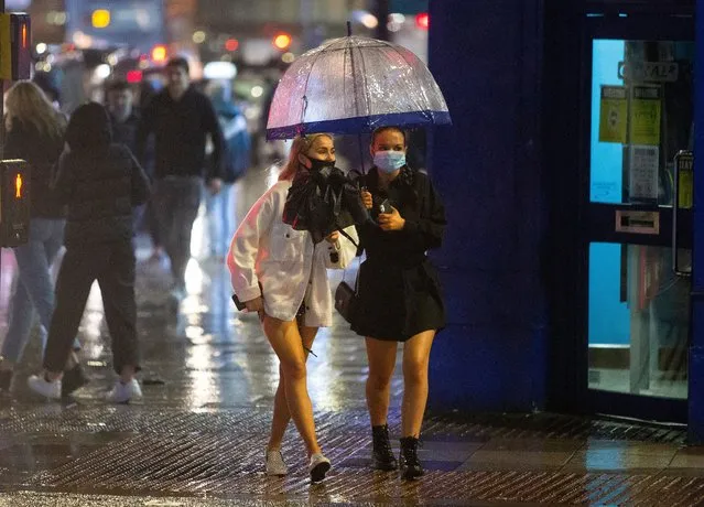 Two girls protect themselves from the rain in the centre of Cardiff, UK on November 20, 2020 where shops are open and people are out in numbers taking advantage of buying nonessential items in the run-up to Christmas. Restrictions across Wales have been relaxed following a two-week “firebreak” lockdown. (Photo by  Huw Evans Picture Agency/The Sun)