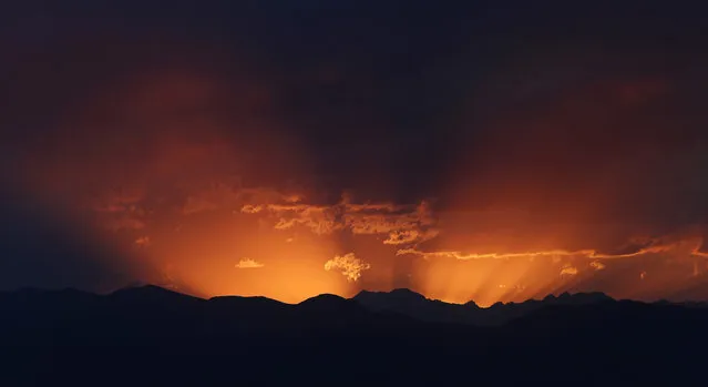 The setting sun lights the evening sky behind the mountains west of Denver late Thursday, June 29, 2017. Forecasters predict that the warm weather will relent on Friday before the heat returns over the Fourth of July holiday, sending temperatures into the mid-90s. (Photo by David Zalubowski/AP Photo)