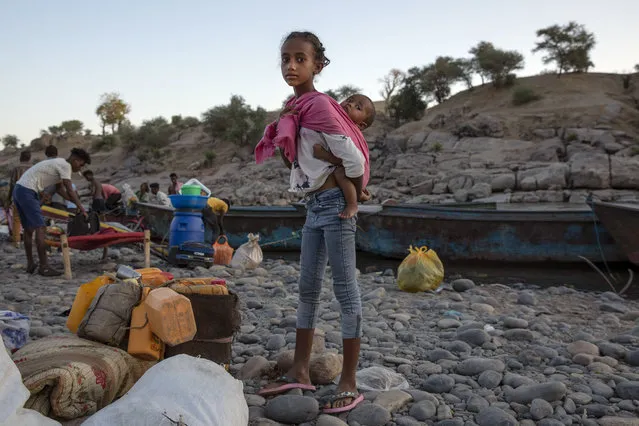 Tigray refugee child carries a baby after they arrive on the banks of the Tekeze River on the Sudan-Ethiopia border, in Hamdayet, eastern Sudan, Wednesday, December 2, 2020. (Photo by Nariman El-Mofty/AP Photo)