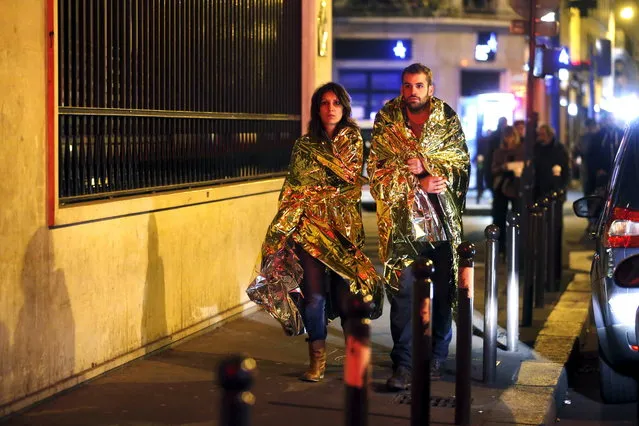 People warm up under protective thermal blankets as they walk on a street near the Bataclan concert hall following fatal attacks in Paris, France, November 14, 2015. (Photo by Christian Hartmann/Reuters)