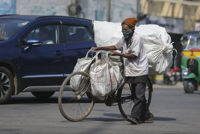 An Indian man wearing face mask as a precaution against the coronavirus pushes his bicycle with load in Hyderabad, India, Thursday, December 17, 2020. (Photo by Mahesh Kumar A./AP Photo)