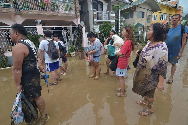Residents stand in the mud as they wait to be evacuated from their flood-hit homes after Typhoon Kalmaegi hit the area in a subdivision of Cebu City in the central Philippines on November 4, 2025. (Photo by Alan Tangcawan/AFP Photo)