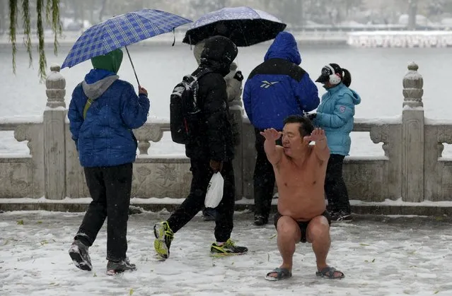 A winter swimmer (front R) stretches after swimming in the Shichahai Lake amid heavy snowfall in Beijing, China, November 22, 2015. (Photo by Reuters/China Daily)