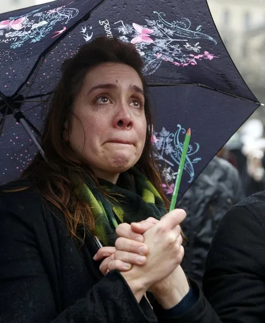 A woman holding a pen cries as she gathers in front of the Notre Dame Cathedral in Paris January 8, 2015 during a minute of silence for victims of the shooting at the Paris offices of weekly satirical newspaper Charlie Hebdo on Wednesday. France began a day of mourning for the journalists and police officers shot dead on Wednesday morning by black-hooded gunmen using Kalashnikov assault rifles. (Photo by Jacky Naegelen/Reuters)