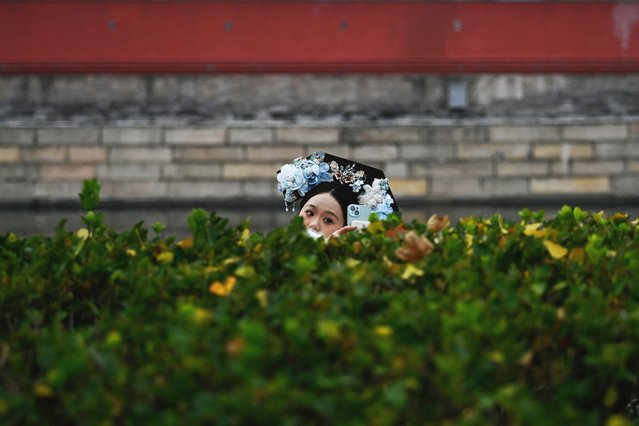 A woman wearing tranditional clothes takes a selfie near the Forbidden City in Beijing on November 6, 2025. (Photo by Wang Zhao/AFP Photo)