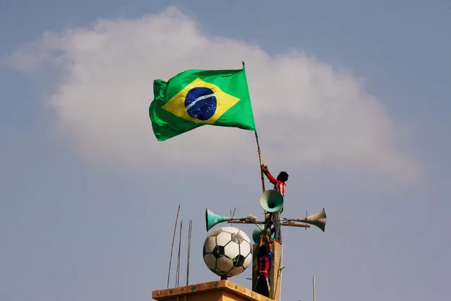 Soccer fans secure Brazil's flag on the rooftop of a community centre, ahead of the FIFA World Cup Russia, in a low-income neighbourhood in Karachi, Pakistan June 4, 2018. (Photo by Akhtar Soomro/Reuters)