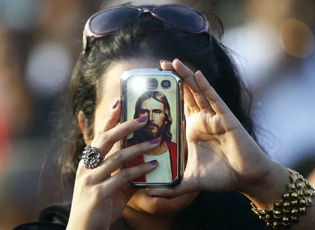 A Catholic faithful takes a picture with a mobile phone before Pope Francis arrives to lead mass in Colombo, January 14, 2015. Hundreds of thousands of people packed a Colombo oceanfront on Wednesday to see Pope Francis give Sri Lanka its first saint, a climax to a 300-year campaign to recognise the holiness of Indian-born missionary Joseph Vaz. (Photo by Stefano Rellandini/Reuters)