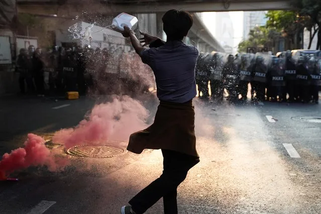 Anti-Thai government protester throws a liquid during a clash with riot police after protesters showed up at a rally for Myanmar's democracy outside the embassy, in Bangkok, Thailand on February 1, 2021. (Photo by Athit Perawongmetha/Reuters)