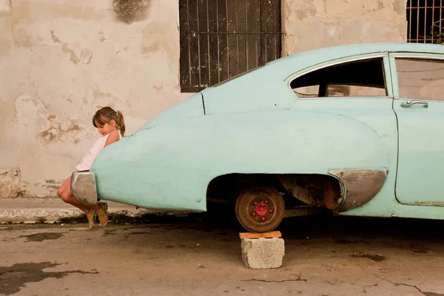 “Innocence and Icon”. The classic American car has become a symbol and staple throughout Cuba. In the back streets of Havana, one who has yet to learn of the country’s history, shows her innocence at play. (Photo and caption by Eric Kruszewski/National Geographic Traveler Photo Contest)