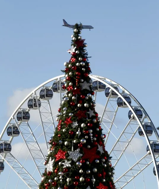 A plane landing in Washington's Reagan National Airport passes a Christmas tree and the “Capital Wheel” at National Harbor in Maryland December 15, 2015. (Photo by Kevin Lamarque/Reuters)
