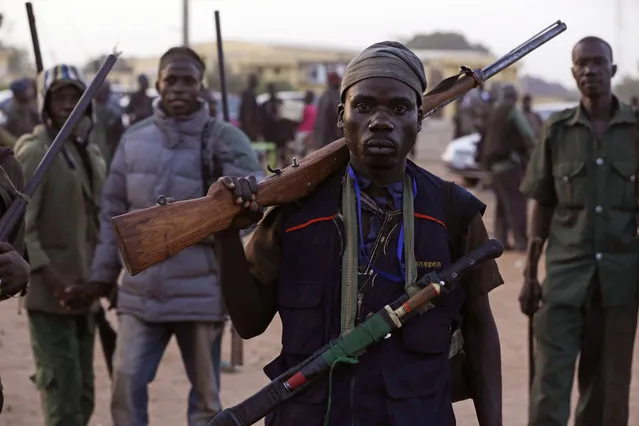 In this file photo taken on Wednesday, November 25, 2014, vigilantes and local hunters armed with locally made guns gather before they go on patrol in Yola, Nigeria,  Islamic extremists are rampaging through villages in northeast Nigeria's Adamawa state, killing, burning and looting with no troops deployed to protect civilians, fleeing villagers said Wednesday, January 28, 2015. (Photo by Sunday Alamba/AP Photo)