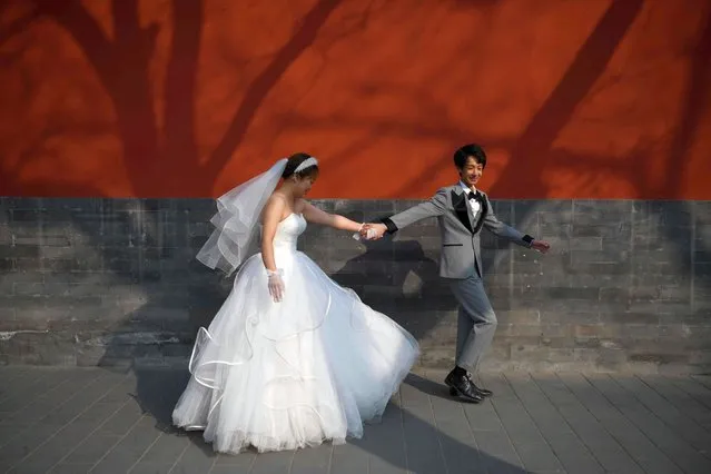 A couple poses for wedding photos on a street near the Forbidden City in Beijing on February 26, 2021. (Photo by Greg Baker/AFP Photo)