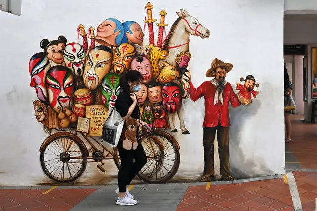 A woman walks past a mural on a wall along a street in Singapore on February 17, 2021. (Photo by Roslan Rahman/AFP Photo)