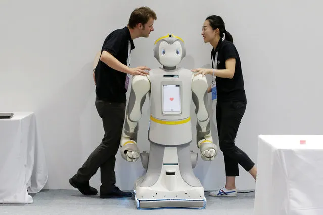 Staff chat next to a P-Care robot at the WRC in Beijing, China on August 15, 2018. (Photo by Jason Lee/Reuters)