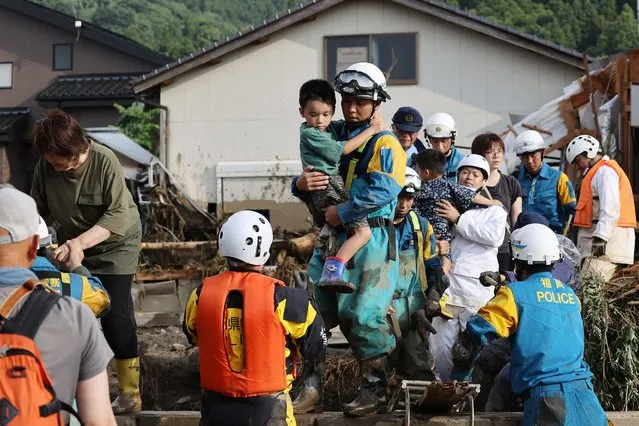 Residents are rescued following a flood in their street in Tanushimarumachi in the city of Kurume, Fukuoka prefecture, on July 10, 2023, after heavy rains hit wide areas of Kyushu island. One person was killed and hundreds of thousands were urged to evacuate their homes in southwestern Japan on July 10, as forecasters warned of the “heaviest rain ever” in the region. (Photo by JIJI Press/AFP Photo)