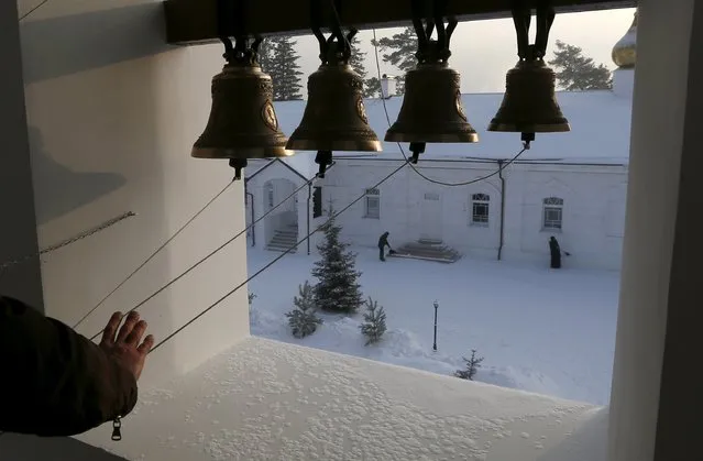 A bell ringer performs before an evening service as monks and priests remove snow in a compound of the Uspensky male monastery, during preparations for the Orthodox Christmas night service in the vicinity of the Siberian city of Krasnoyarsk, Russia, January 6, 2016. (Photo by Ilya Naymushin/Reuters)