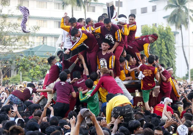 A few Catholic devotees manage to get closer to either kiss or rub with towels, the cross of the image of the Black Nazarene as they take part in a raucous procession to celebrate its feast day in Manila, Philippines, Saturday, January 9, 2016. (Photo by Bullit Marquez/AP Photo)