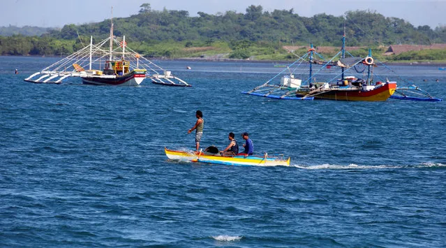 Fishermen ride on a small boat past their big boats as they prepare to fish at disputed Scarborough Shoal,  at the coastal village of Cato in Infanta, Pangasinan in the Philippines, November 3, 2016. (Photo by Erik De Castro/Reuters)