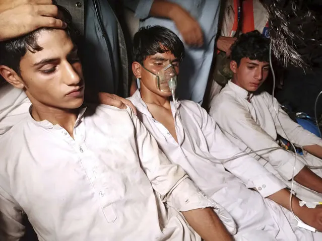Youngsters, left, who were trapped in a broken cable car, receive first aid following their rescue, in Pashto village, a mountainous area of Battagram district in Pakistan's Khyber Pakhtunkhwa province, Tuesday, August 22, 2023. Army commandos using helicopters and a makeshift chairlift rescued eight people from a broken cable car dangling hundreds of meters (feet) above a canyon Tuesday in a remote part of Pakistan, authorities said. (Photo by Nasir Mahmood/AP Photo)