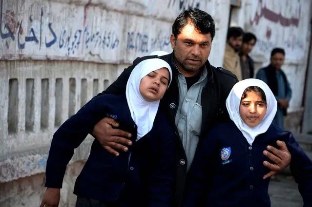 An Afghan man assists two schoolgirls in the vicinity of an attack from a building close to the Pakistan consulate in Jalalabad on January 13, 2016. A suicide bombing followed by gunfire rocked an area near the Pakistani consulate in the eastern Afghan city of Jalalabad on January 13, killing at least two police officers, officials said. (Photo by Noorullah Shirzada/AFP Photo)
