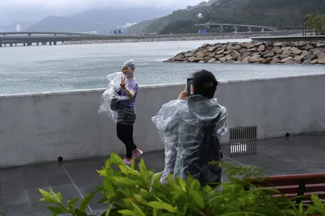 People pose for photographs in the wind during Typhoon Saola in Tseung kwan O, in Hong Kong on Saturday, September 2, 2023. Typhoon Saola made landfall in southern China before dawn Saturday after nearly 900,000 people were moved to safety and most of Hong Kong and other parts of coastal southern China suspended business, transport and classes. (Photo by Billy H.C. Kwok/AP Photo)