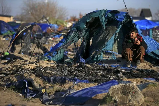 An Afghan migrant sits in front of a burnt dismantled shelter in the camp known as the “Jungle”, a squalid sprawling camp in Calais, northern France, January 19, 2016. French authorities have asked migrants living in makeshift shelters to respect an unoccupied 100 meter zone from the fence barrier which protects the road that leads to the ferry terminal. (Photo by Pascal Rossignol/Reuters)