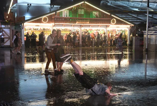 A visitor to the Oktoberfest takes a bath in a puddle while Sturmtief Fabienne is passing through in Bavaria, Munich on September 23, 2018. The world's largest fair lasts from 22.09. to 07.10.2018. (Photo by Felix Hörhager/DPA/Picture Alliance via Getty Images)