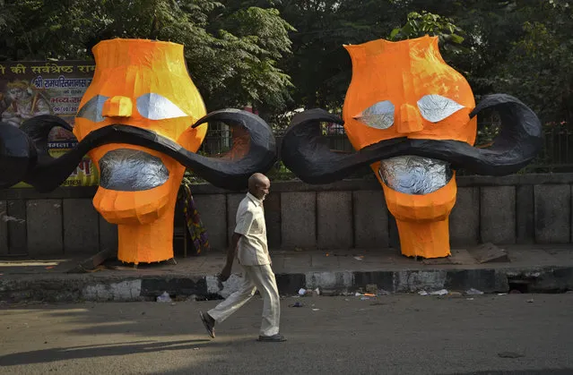 A man walks past parts of effigies of demon king Ravana displayed for sale on a pavement ahead of Dussehra festival in New Delhi, India, Sunday, October 14, 2018. The festival commemorating victory of Hindu god Rama over Ravana ends with burning of these effigies, signifying the victory of good over evil. (Photo by R.S. Iyer/AP Photo)