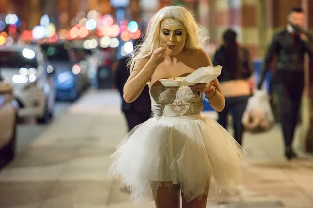 This corset-clad bride is pleased with her late-night snack durind Halloween night in Manchester, England on Saturday, October 27, 2018. The single-digit temperatures didn't stop some partygoers from dressing in a sheer costume or going bare-chested. (Photo by Mercury Press)