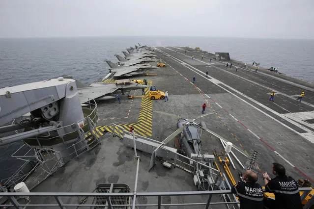 In this Tuesday, March 17, 2015 photo, French sailors work on the flight deck of the French Navy aircraft carrier Charles de Gaulle in the Persian Gulf. Aircraft aboard the French carrier are flying bombing and reconnaissance missions as part of a U.S.-led coalition targeting Islamic State militants in Iraq. (Photo by Hasan Jamali/AP Photo)