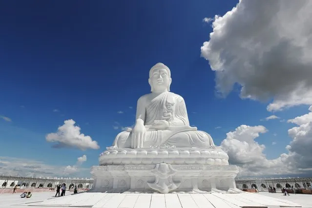 Laborers work while visitors stand below the sitting Maravijaya Buddha marble statue, Friday, July 21, 2023, in Naypyitaw, Myanmar. (Photo by Aung Shine Oo/AP Photo)