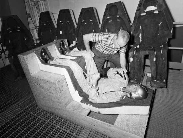 Mercury Astronaut Alan Shepard Jr. lies in the space vehicle couch that was molded especially for him while Flight Surgeon William Douglas checks the fit, December 7, 1959. In the background are the couches made for the other six astronauts. One of the seven astronauts will make the first U.S. manned flight into space, but neither the man nor the date for attempting the flight has been chosen. (Photo by AP Photo)