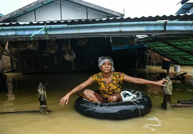 A residents uses a buoy to move through a flooded house after heavy rains in Bago township in Myanmar's Bago region on October 10, 2023. Floods sparked by record October rain hit parts of southern Myanmar on October 9, inundating roads and fields and sending residents fleeing for higher ground. (Photo by Sai Aung Main/AFP Photo)