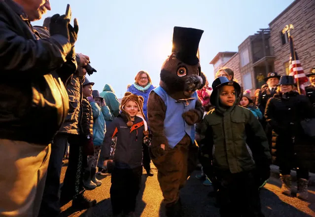 A costumed Jimmy the Groundhog mascot makes his way through a crowd gathered at the 2016 Groundhog Prognostication gathering in Sun Prairie, Wis. Tuesday, February 2, 2016. Escorting him at left is Asher Wotruba, who was born on Groundhog Day five years ago during a blizzard which dumped more than 18 inches of snow in the area.  Overcast skies prevented Jimmy from seeing his shadow, supposedly signaling an early spring arrival according to the tradition. (Photo by John Hart,/Wisconsin State Journal via AP Photo)