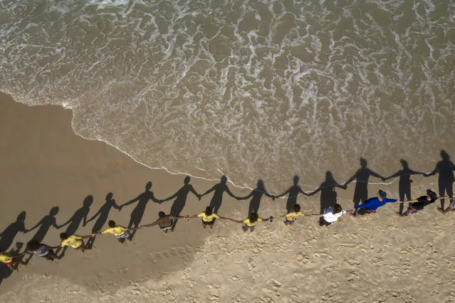 People create a human chain along the Sao Conrado coast for a symbolic group hug with the sea, to mark World Oceans Day, in Rio de Janeiro, Brazil, Thursday, June 8, 2023. (Photo by Bruna Prado/AP Photo)