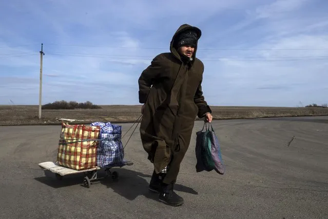 A woman pulls her bags as she is about to cross the Uspenka border crossing between Ukraine and Russia, southeast from Donetsk, March 15, 2015. (Photo by Marko Djurica/Reuters)