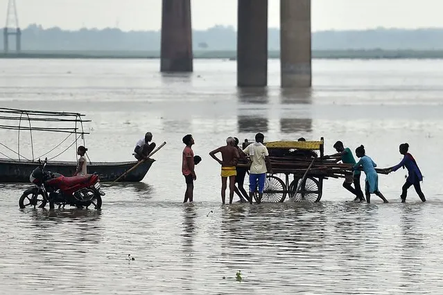 People move their shelters from the banks of the Ganges River as the water level of the Ganges and Yamuna rises in Allahabad on July 31, 2021. (Photo by Sanjay Kanojia/AFP Photo)