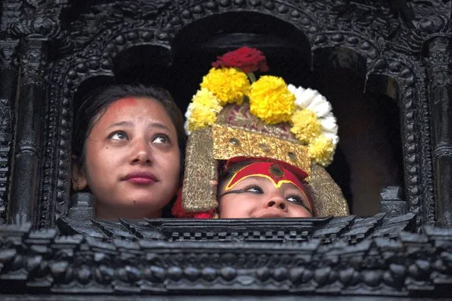 Living god Ganesh looks out from a window during the annual Indra Jatra festival in Kathmandu, Nepal, Friday, September 9, 2022. The girl child revered as the living goddess was pulled around the main parts of the capital Friday by devotees on a wooden chariot as tens of thousands of people lined up the old city to get a glimpse and blessing. (Photo by Niranjan Shrestha/AP Photo)