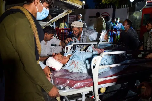 Medical and hospital staff bring an injured man on a stretcher for treatment after two blasts, which killed at least five and wounded a dozen, outside the airport in Kabul on August 26, 2021. (Photo by Wakil Kohsar/AFP Photo)