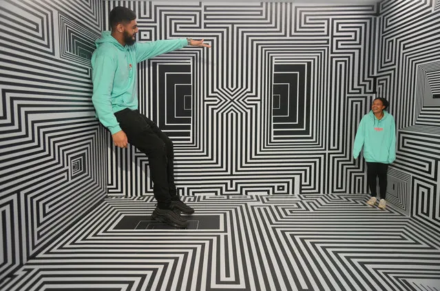 Employees Nomair and Pena pose within "Ames Room" at “The Way I See Things” immersive installation and attractions exhibition at Twist Museum in London, Britain on November 15, 2022. (Photo by Toby Melville/Reuters)