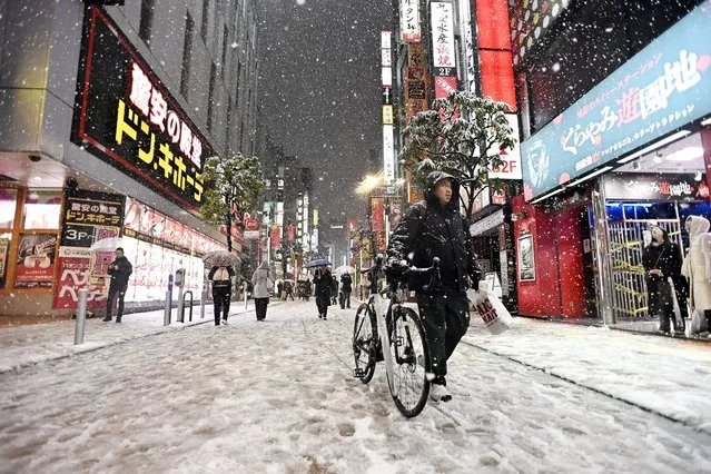 A man walks on the snow covered street with his bike as citizens walk with umbrellas during the first snowfall of the year in Tokyo, Japan on February 05, 2024. (Photo by David Mareuil/Anadolu via Getty Images)