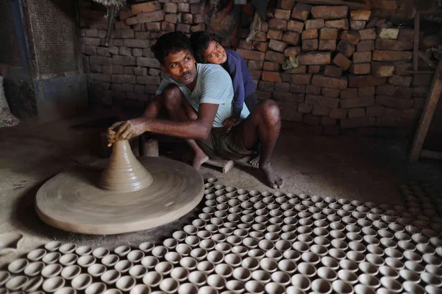 An Indian potter makes earthen lamps ahead of Diwali festival in Prayagraj, India. Wednesday, October 27, 2021. People buy earthen lamps to decorate their homes during Diwali, the annual Hindu festival of lights which will be celebrated on Nov. 4. (Photo by Rajesh Kumar Singh/AP Photo)