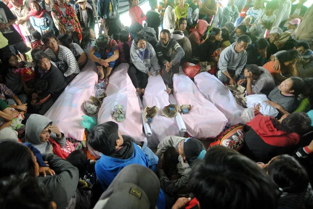 Balinese sit next to the bodies of landlside victims at Songan village in Kintamani, Indonesia resort island of Bali province, February 10, 2017 in this photo taken by Antara Foto. (Photo by Nyoman Budhiana/Reuters/Antara Foto)