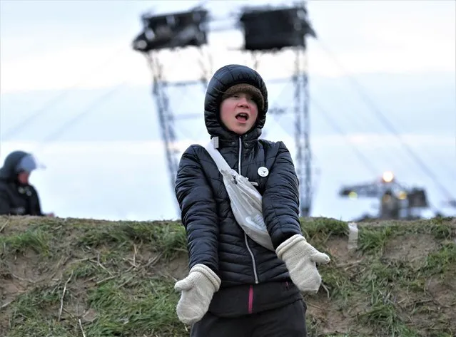 Climate activist Greta Thunberg stands between Keyenberg and Lützerath under police guard on the edge of the open pit mine and dances in Erkelenz, Germany, Sunday, January 15, 2023. The energy company RWE wants to excavate the coal lying under Luetzerath, for this purpose, the hamlet on the territory of the city of Erkelenz at the opencast lignite mine Garzweiler II is to be demolished. (Photo by Federico Gambarini/dpa via AP Photo)