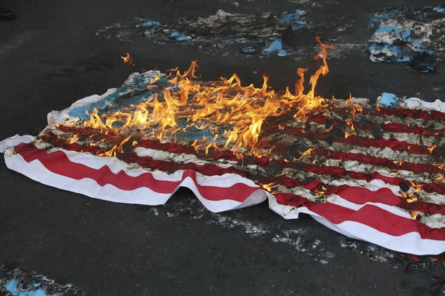 A mock U.S. flag is set on fire by demonstrators during a rally in front of the former U.S. Embassy commemorating the anniversary of its 1979 seizure in Tehran, Iran, Thursday, November 4, 2021. The embassy takeover triggered a 444-day hostage crisis and break in diplomatic relations that continues to this day. (Photo by Vahid Salemi/AP Photo)
